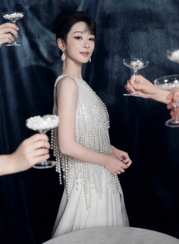 搜狐娱乐讯 近日，一组杨紫的生日大片释出。图中，她穿着珍珠流苏礼服，在珍珠酒杯环绕中，华贵又复古。